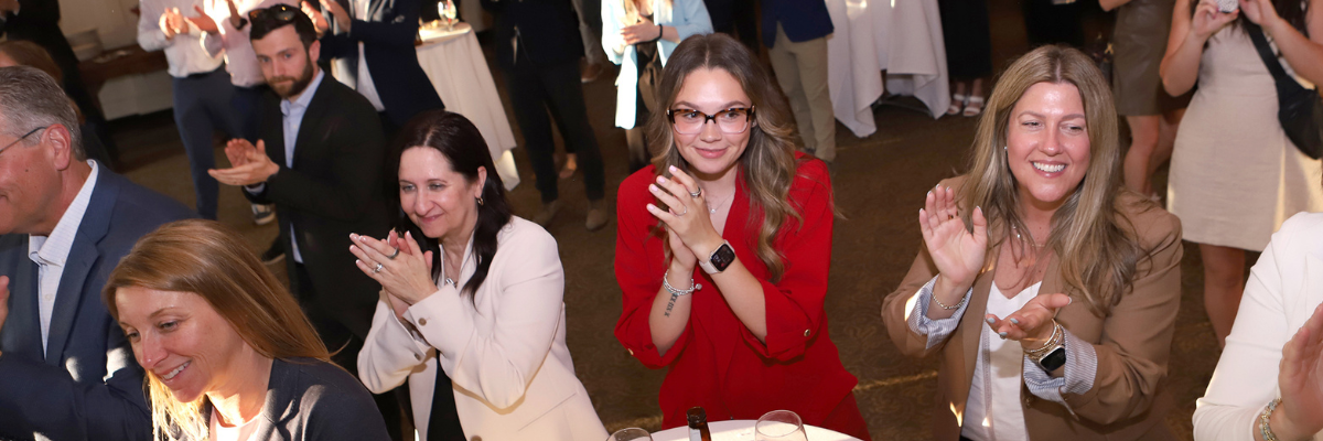 A group of people standing and clapping at an indoor event.