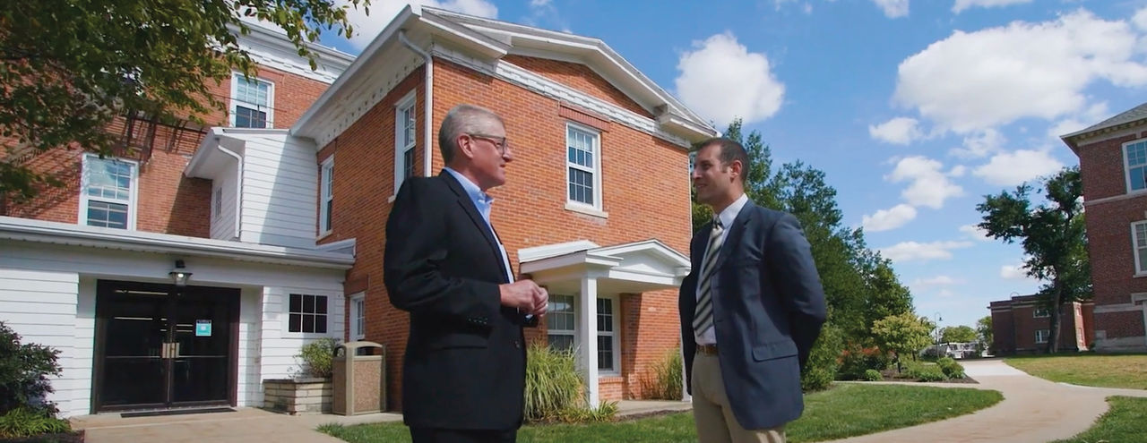 Cornell College building with two people in front.