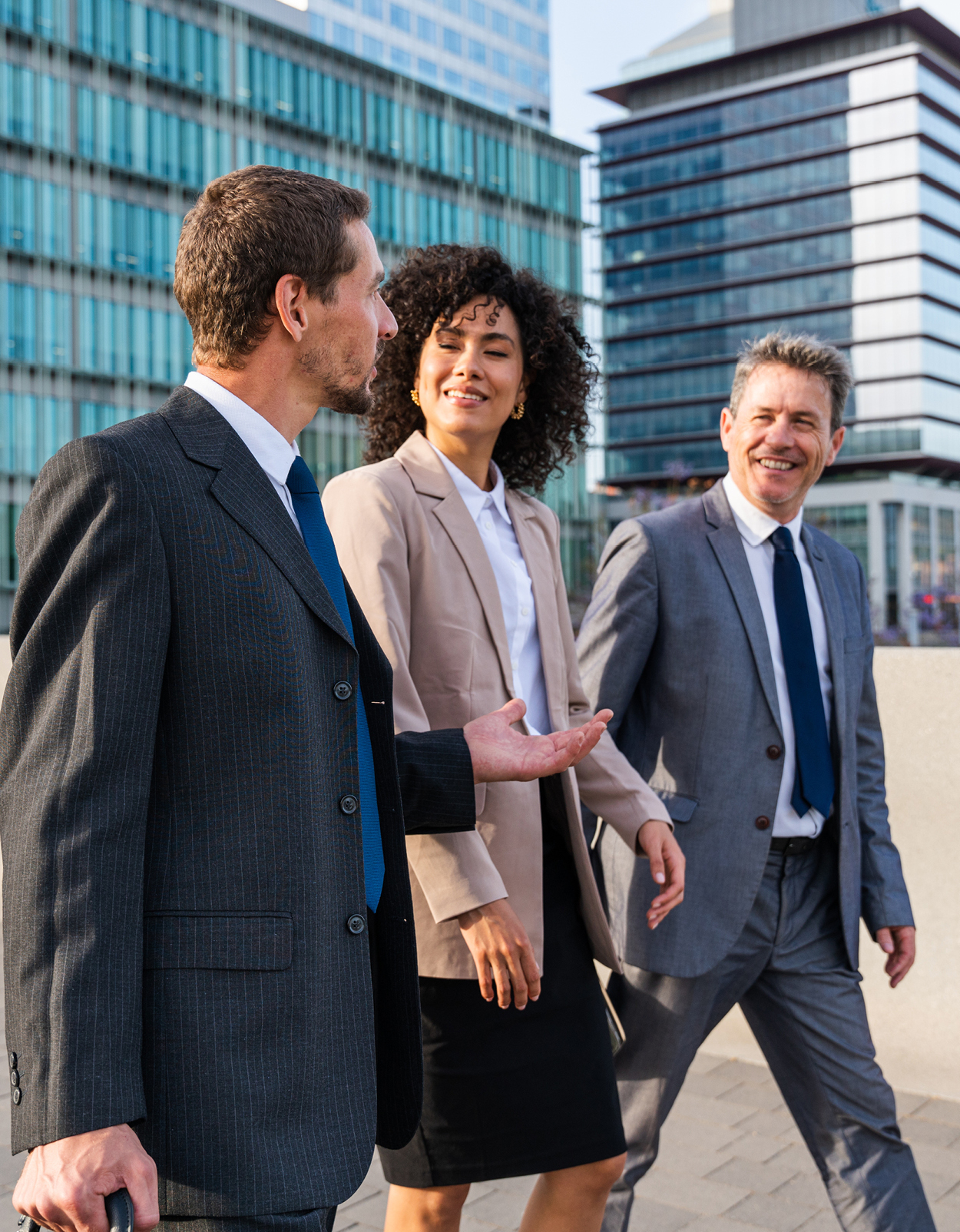 Business colleagues walking and talking outside of office building.