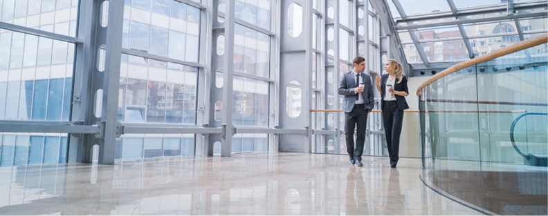 Two professionals walking through a bright office atrium.