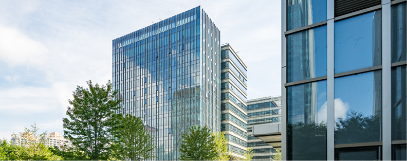 Modern glass office buildings surrounded by trees.