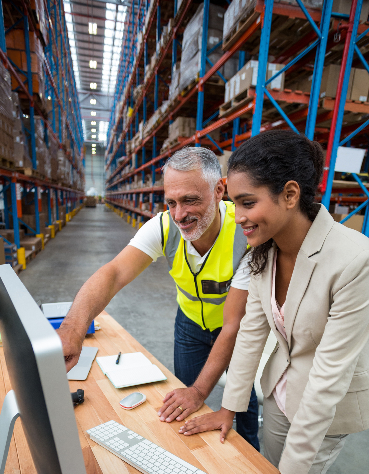 Warehouse manager and employee collaborating at a computer.