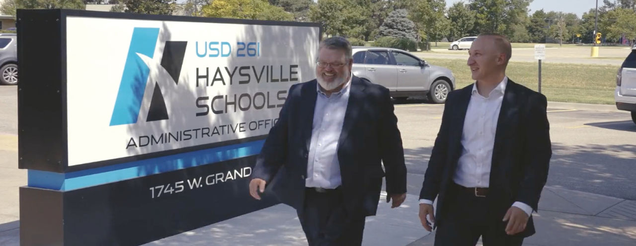 First American colleague with someone from Haysville School District outside in front of sign.