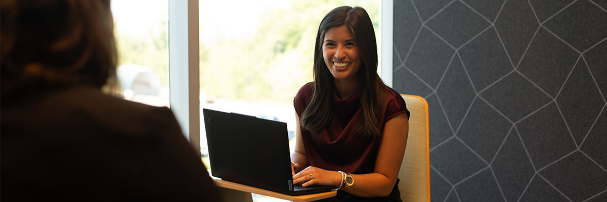 Colleague using a laptop in a modern office meeting space.