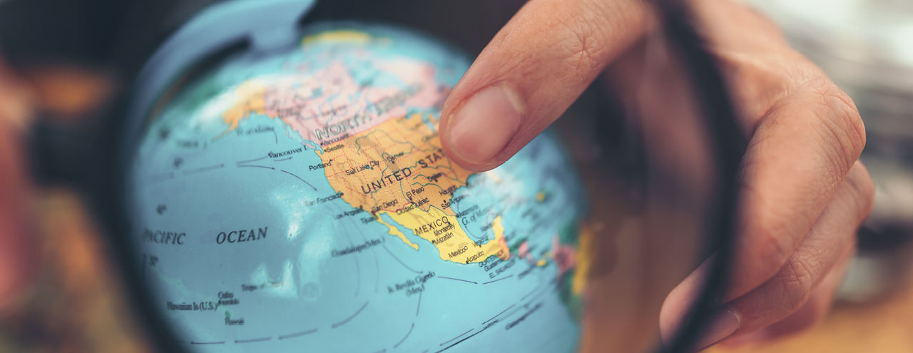 Hand pointing to the U.S. on globe