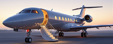 Private jet with boarding stairs extended at sunset.