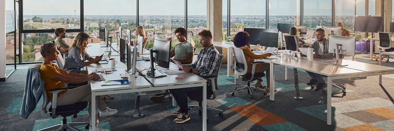 Colleagues working and collaborating on computers in modern office