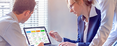 Business professionals pointing at computer screen with software