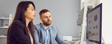 Two people reviewing stats on a desktop screen