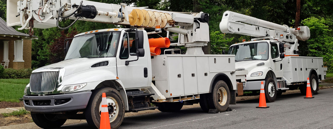 Two utility fleet vehicles on the side of the road.